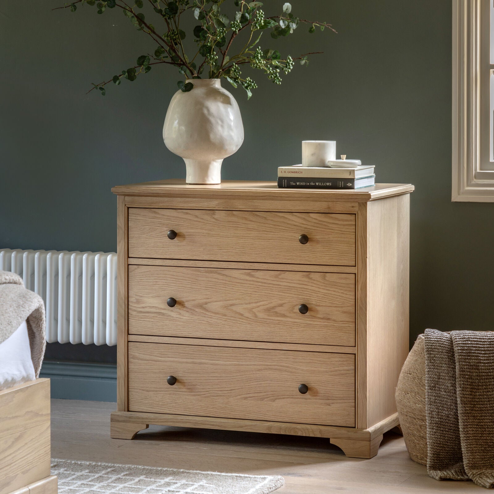 Modern compact oak chest of drawers with three drawers in a neutral bedroom setting
