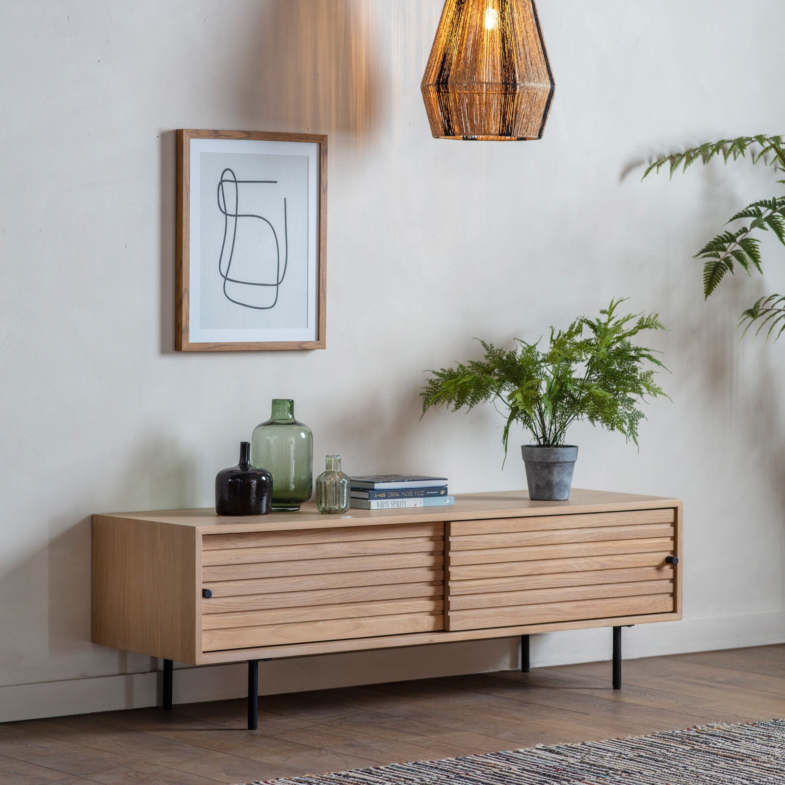 Soja TV stand with routed detailing in natural oak finish with black metal legs and sliding doors | malletandplane.com