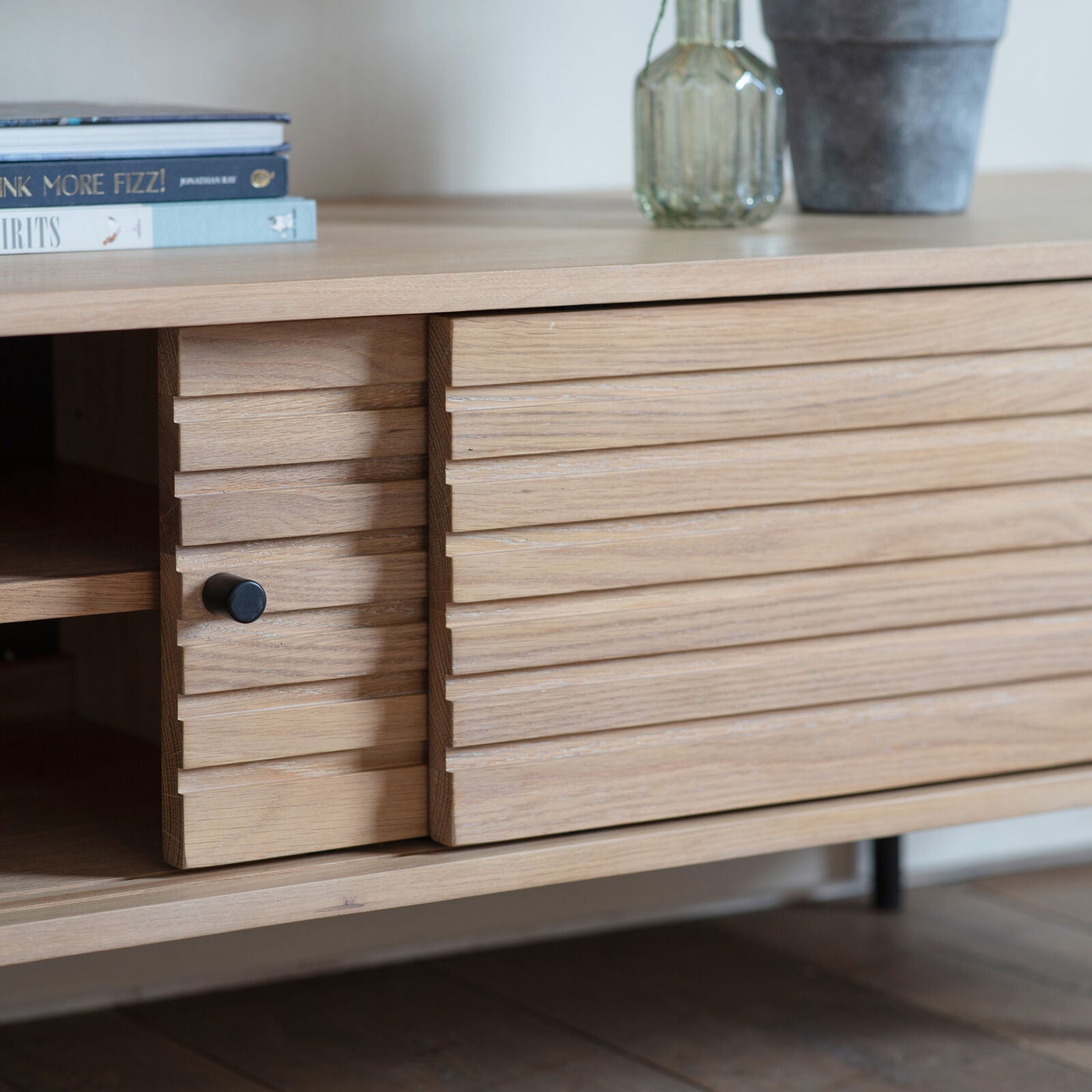 Soja TV stand with routed detailing in natural oak finish with black metal legs and sliding doors | malletandplane.com